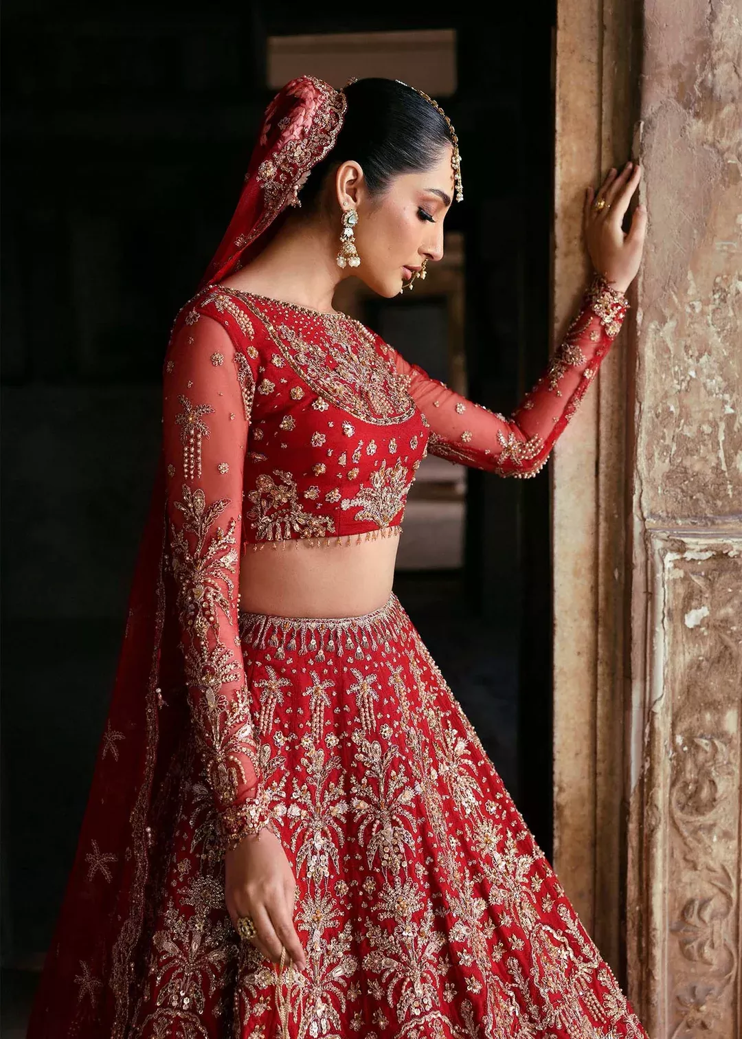 Traditional Pakistani bride wearing heavily embroidered red bridal lehenga